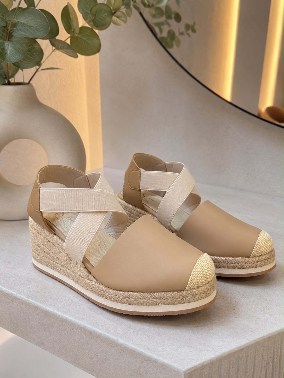 Sandalia de plataforma tipo espadrille para mujer en cuero color taupe, con bandas elásticas cruzadas sobre el empeine y suela cubierta de yute natural.