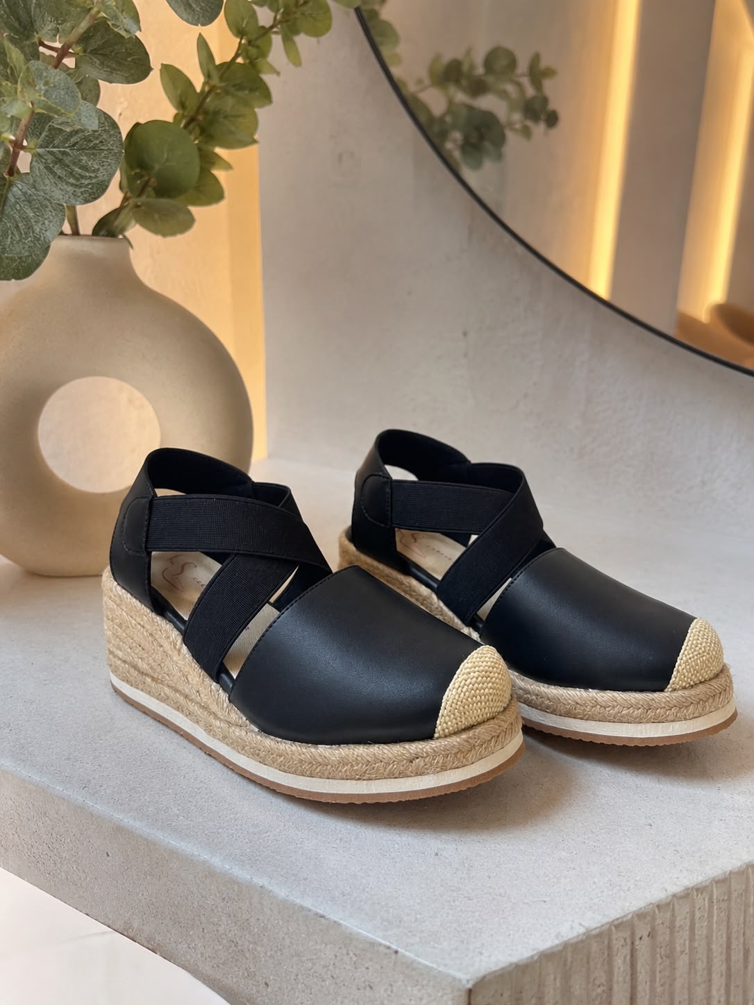 Sandalias de plataforma tipo espadrille en color negro con capellada de cuero, bandas elásticas cruzadas en el empeine y suela cubierta de yute.